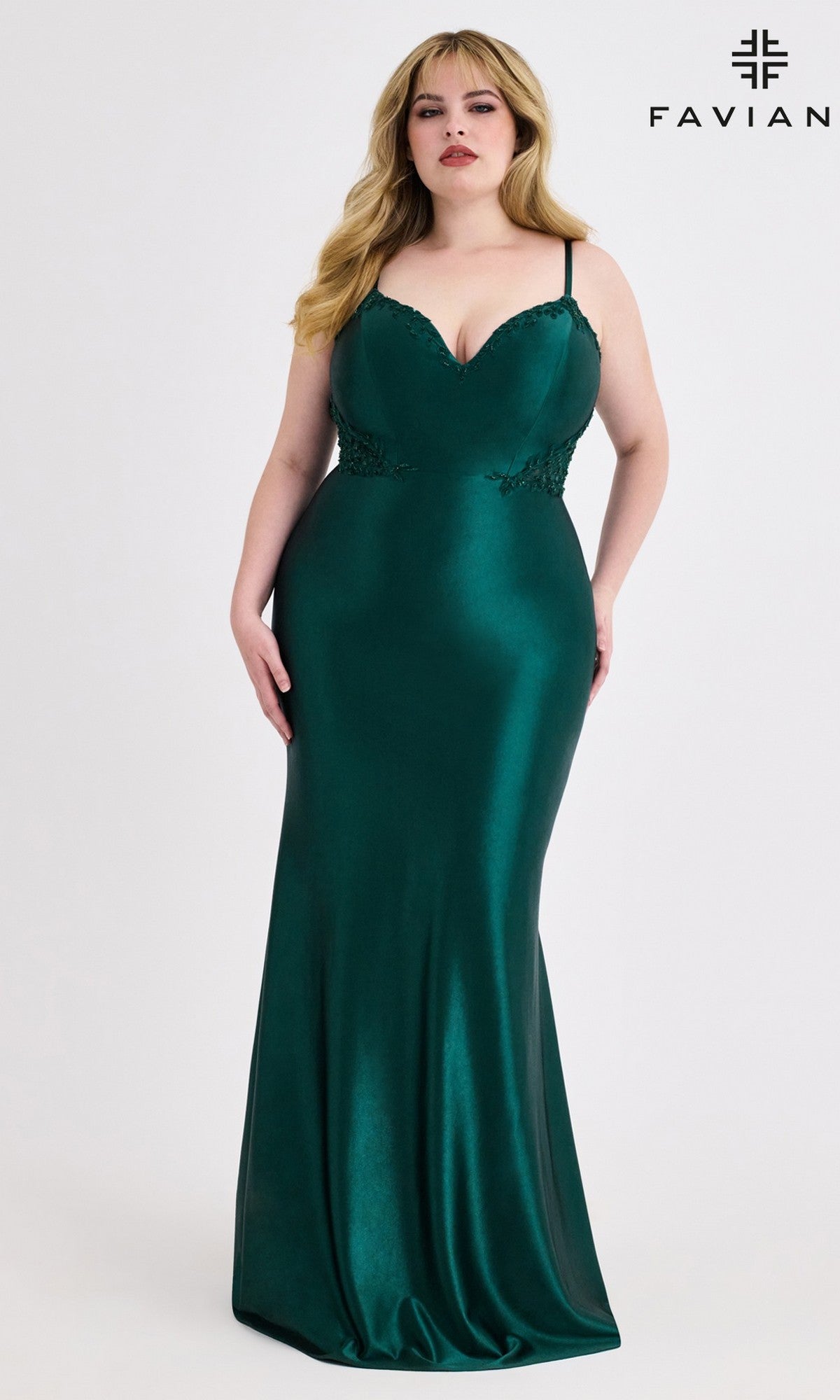 A woman in a fitted, floor-length emerald green Faviana 9600 Beaded-Corset Plus-Size Prom Gown stands against a white background. This elegant dress is ideal for making a statement at any special occasion.